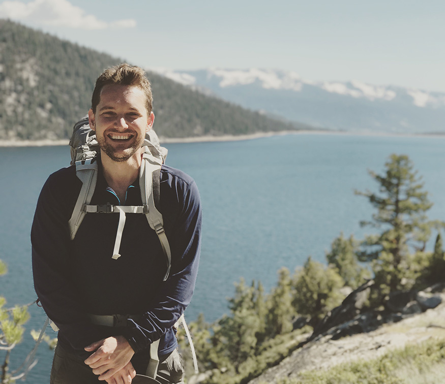 Stephen Haney backpacking in the Sierras. A mountain lake is in the background.